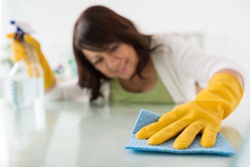 Cleaner wiping desks and shared surfaces in a Croydon office
